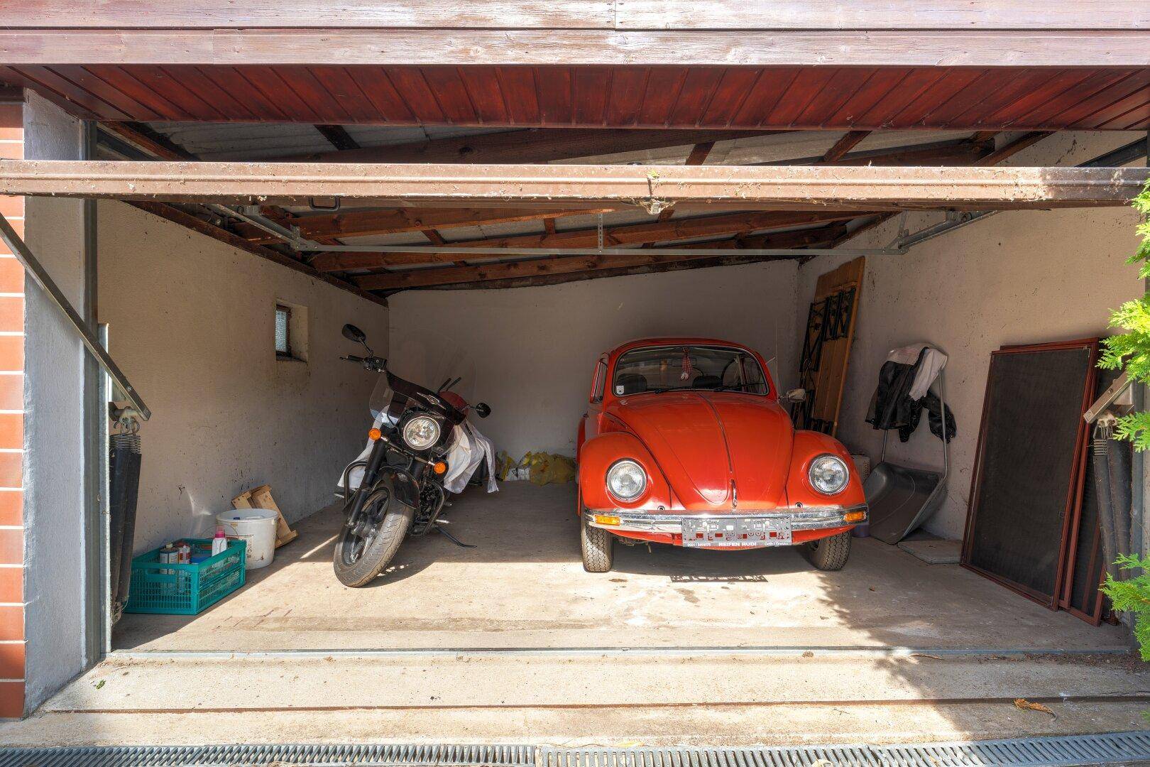 Geräumige Garage mit einem Oldtimer und einem Motorrad, bietet Platz für zwei Fahrzeuge.