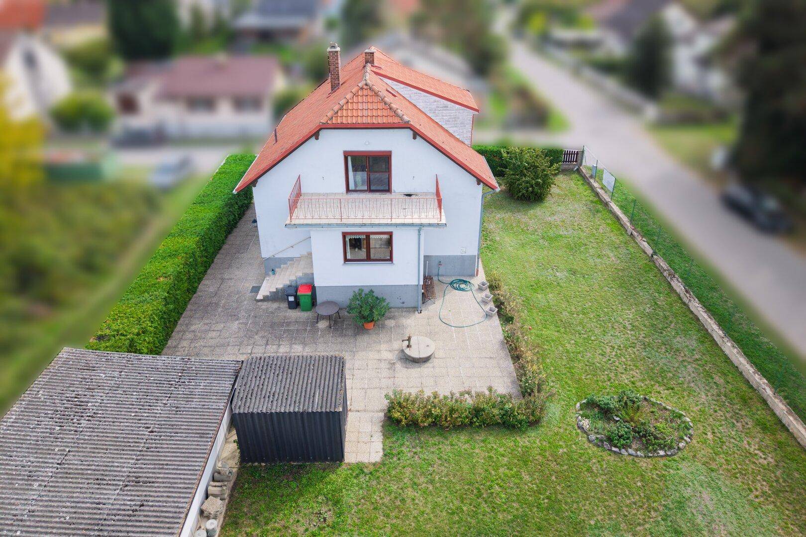 Luftaufnahme des Einfamilienhauses mit gepflegtem Garten, Terrasse und Zufahrt.