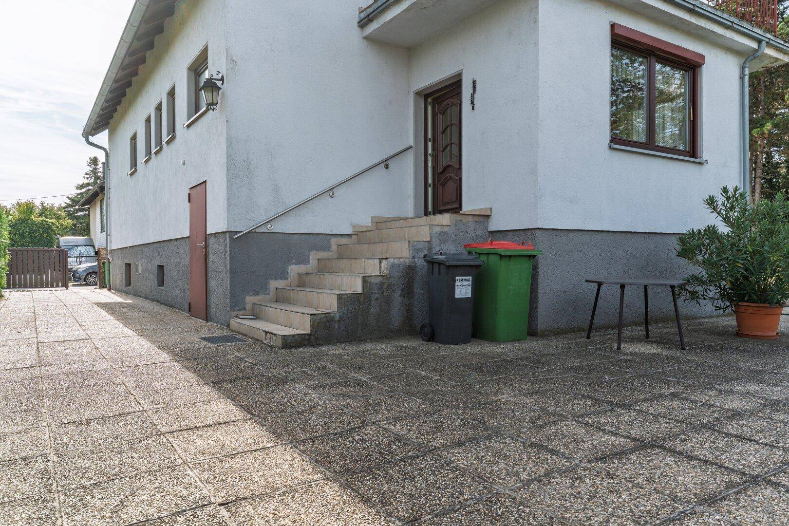 Seitlicher Eingangsbereich des Hauses mit Außentreppe und gepflastertem Zugang.