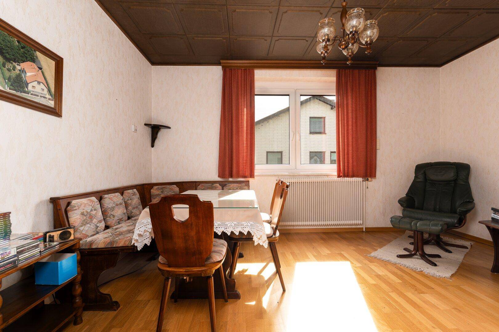Gemütlicher Essbereich mit Eckbank, Holztisch und Blick auf den Garten durch das Fenster.