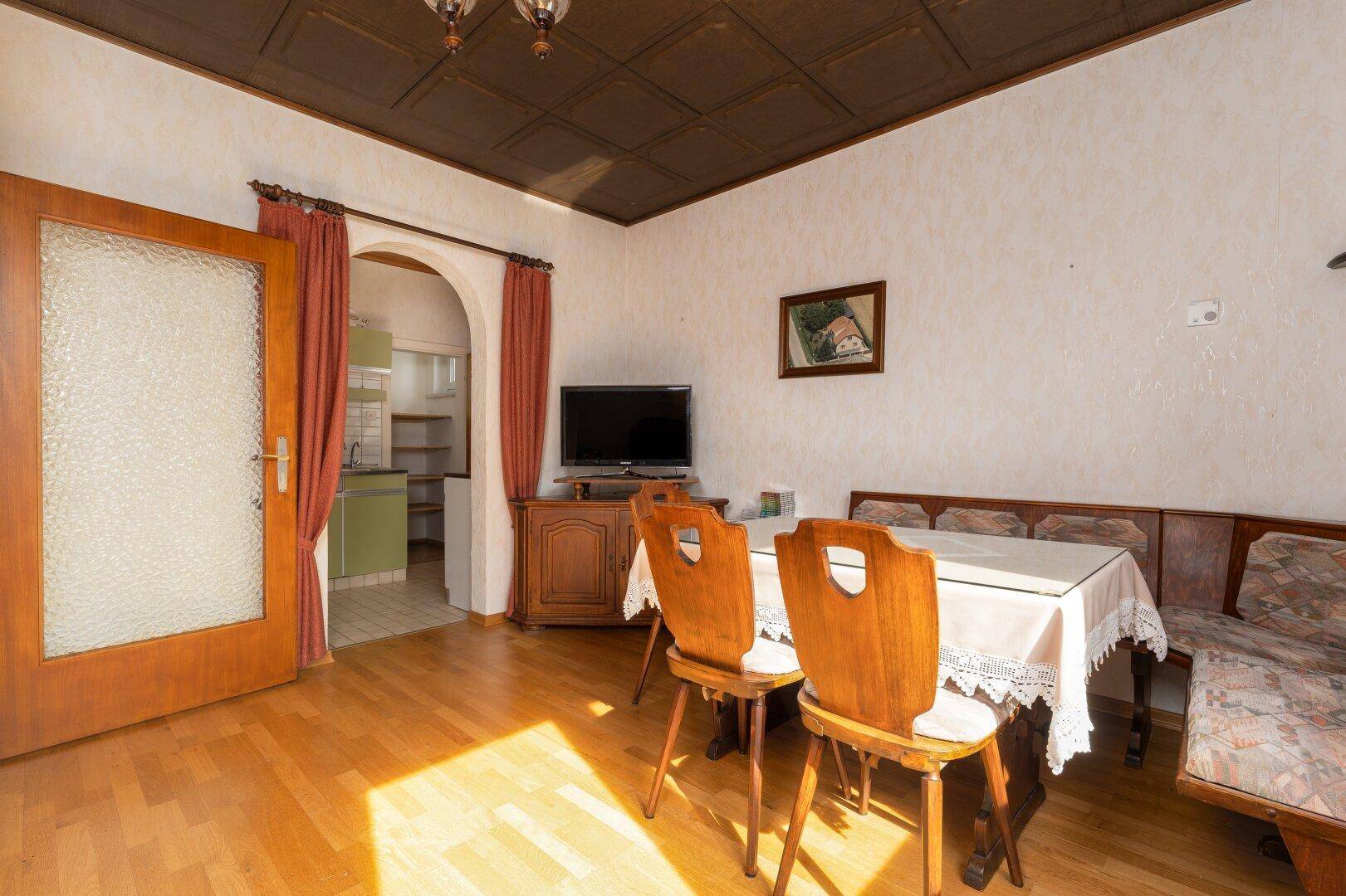 Esszimmer mit traditionellen Holzmöbeln und offenem Durchgang zur Küche.
