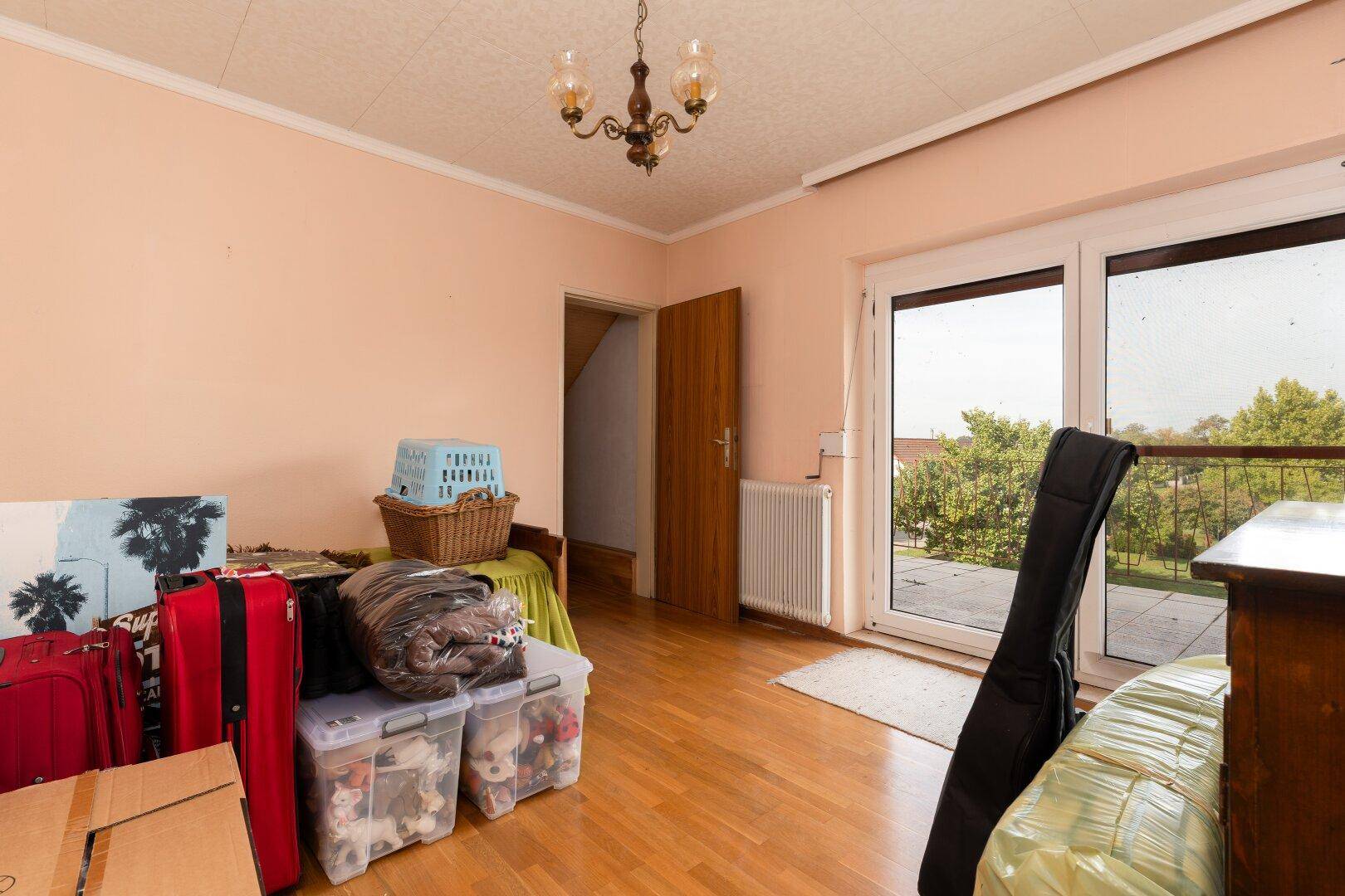 Schlafzimmer mit Zugang zu einem großen Balkon, hell und mit Blick ins Grüne.
