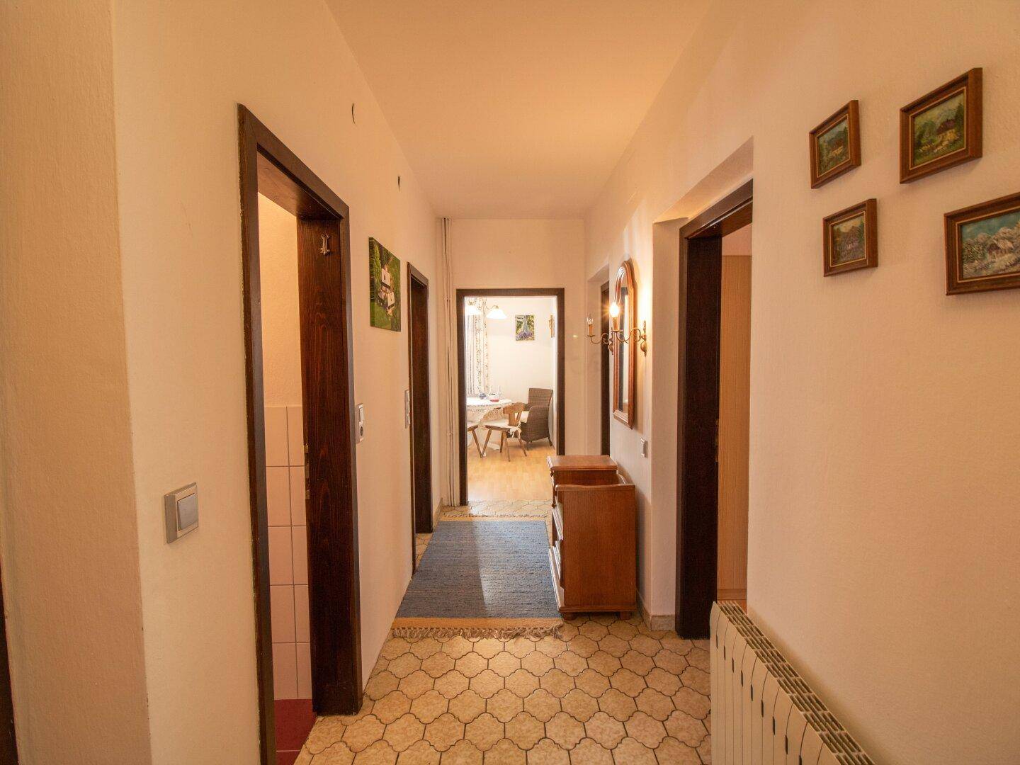 Langer Flur mit Fliesenboden und Zugang zu verschiedenen Räumen im Haus.