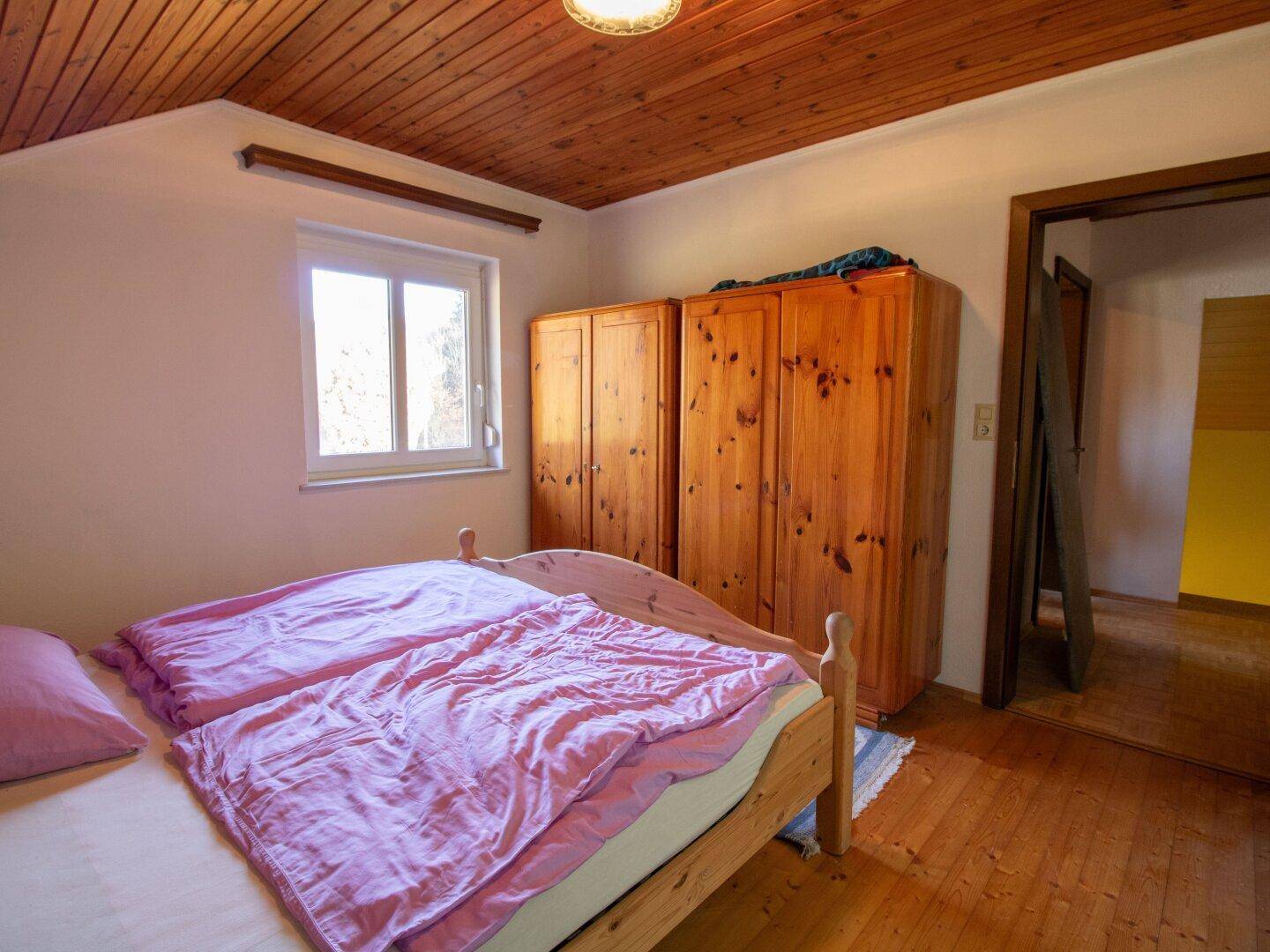 Geräumiges Schlafzimmer mit Holzdecke, Doppelbett und Kleiderschränken.
