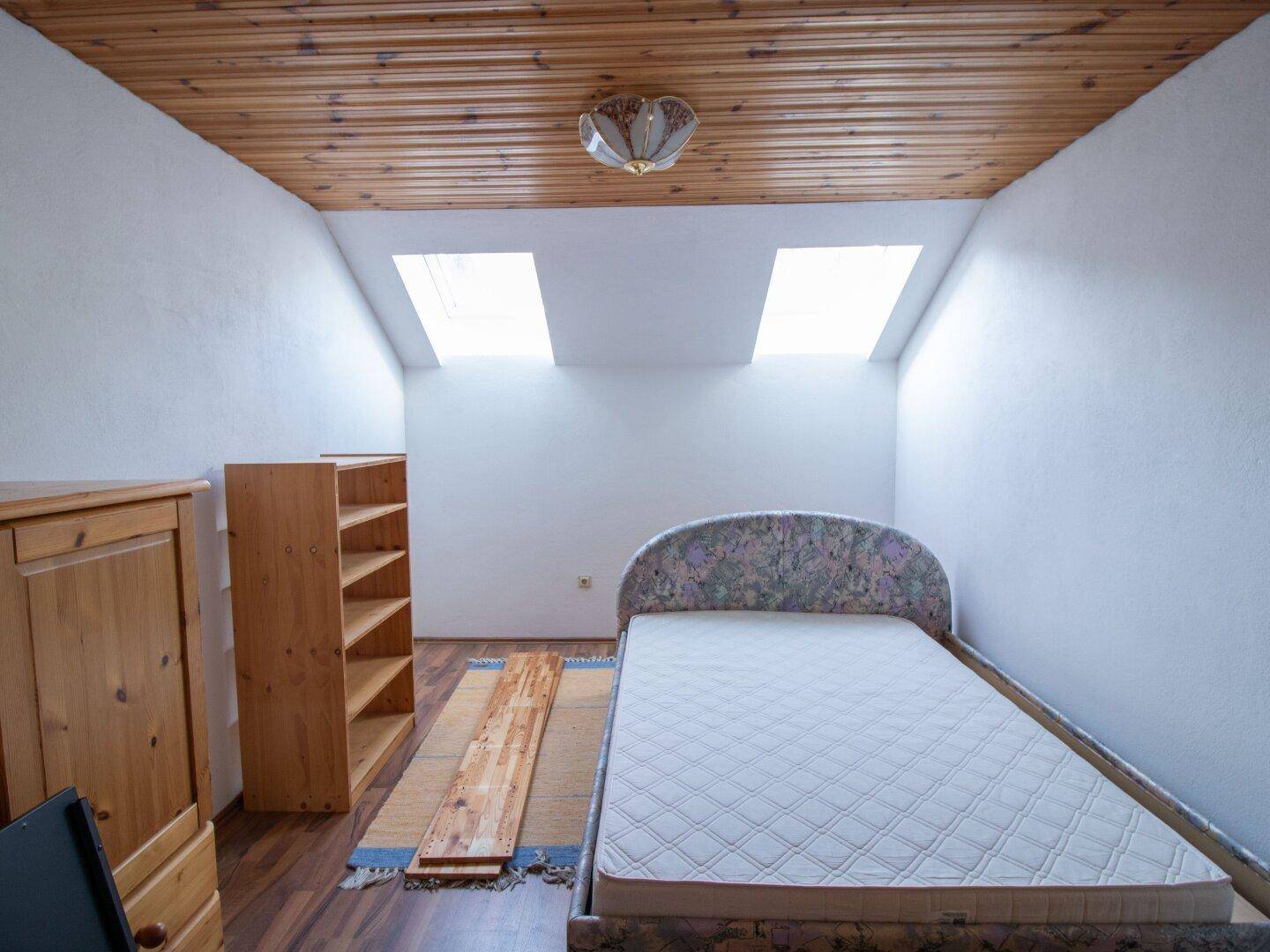 Dachgeschoss-Schlafzimmer mit zwei Dachfenstern und Holzboden, hell und geräumig.