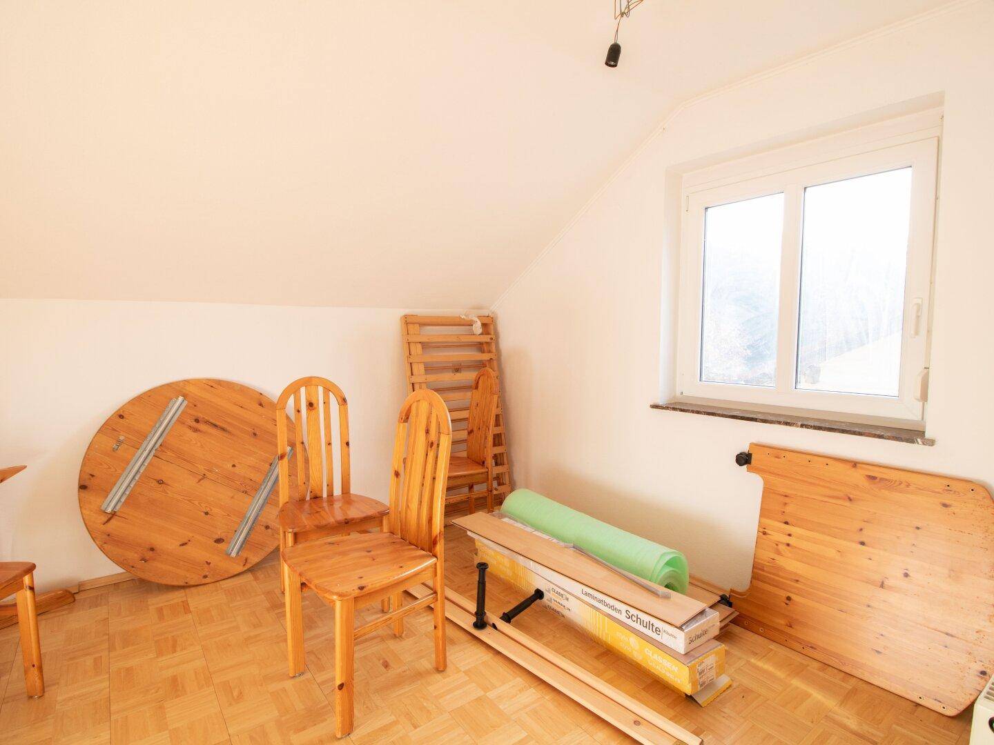 Dachgeschossbereich mit Holztisch und Stühlen, bereit für die Einrichtung.