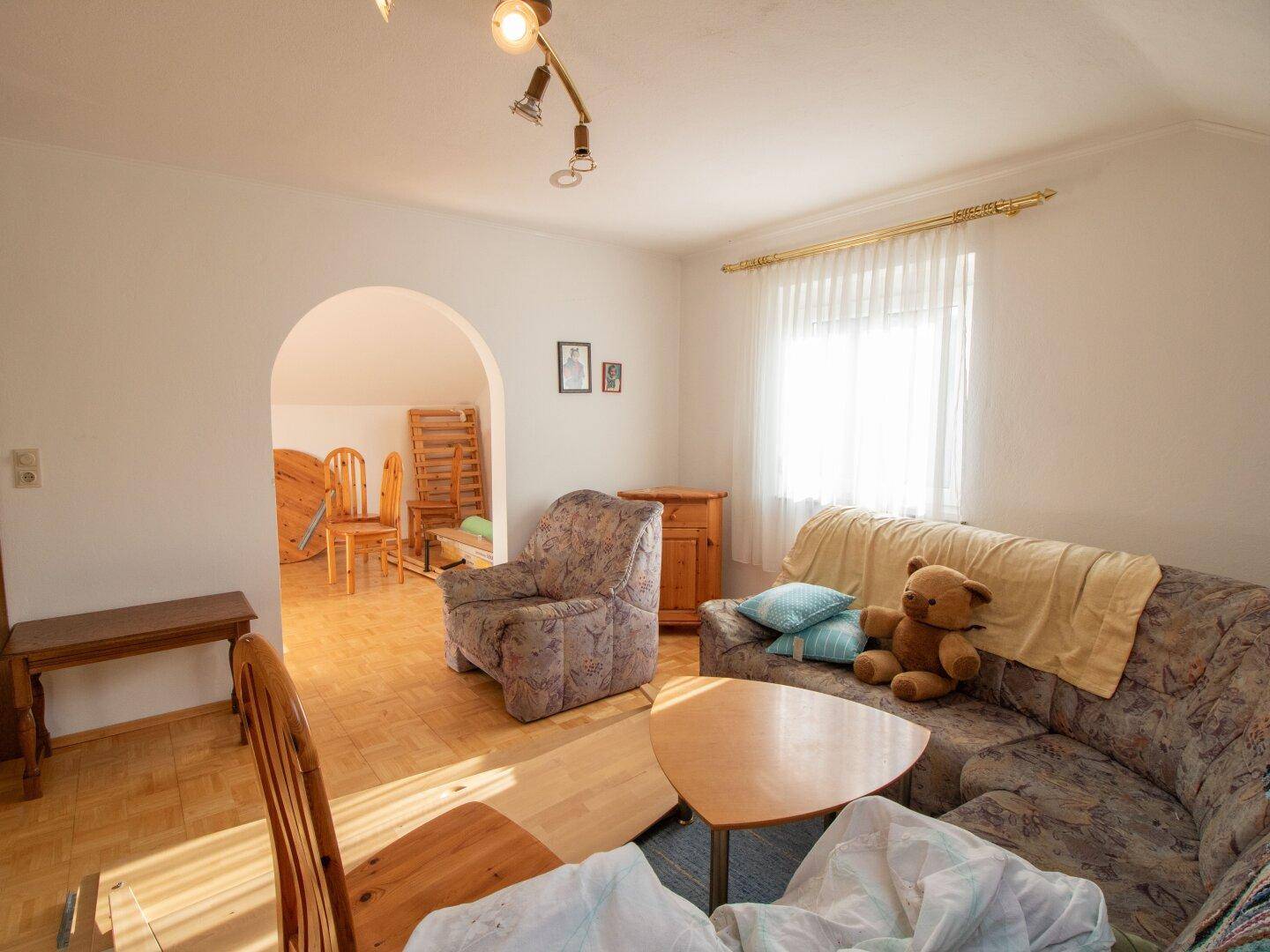 Geräumiges Dachgeschoss-Wohnzimmer mit Sofa und Parkettboden, offener Übergang.