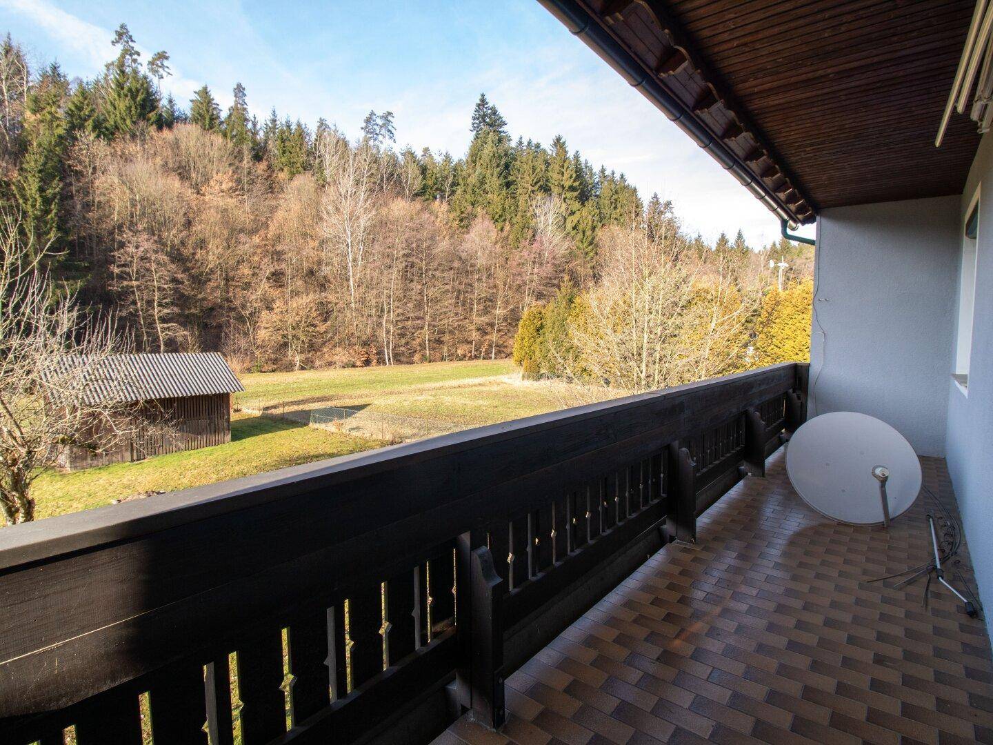 Geräumiger Balkon mit Fliesenboden und weitem Blick auf die umliegende Natur.
