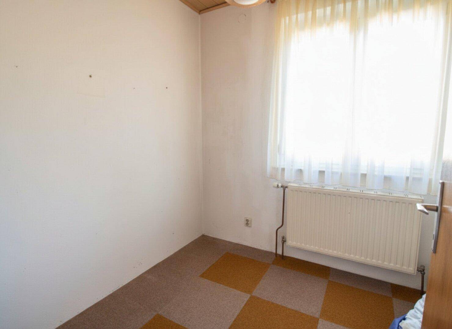 Kleines Schlafzimmer mit Teppichboden und Fenster, einfach und hell.