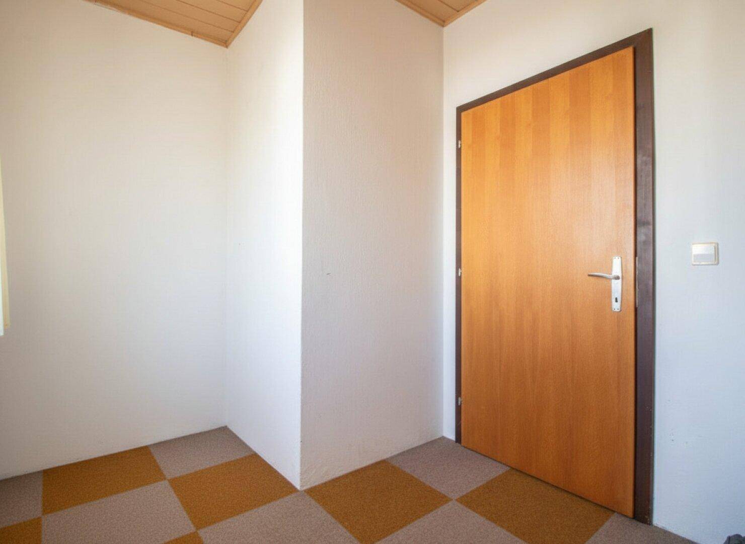 Eingangsbereich mit Holztür und gemustertem Boden, hell und einladend.