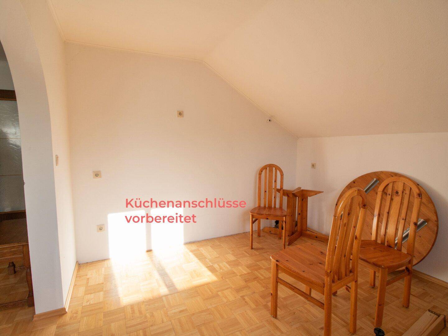 Dachgeschossraum mit vorbereiteten Küchenanschlüssen und Parkettboden.