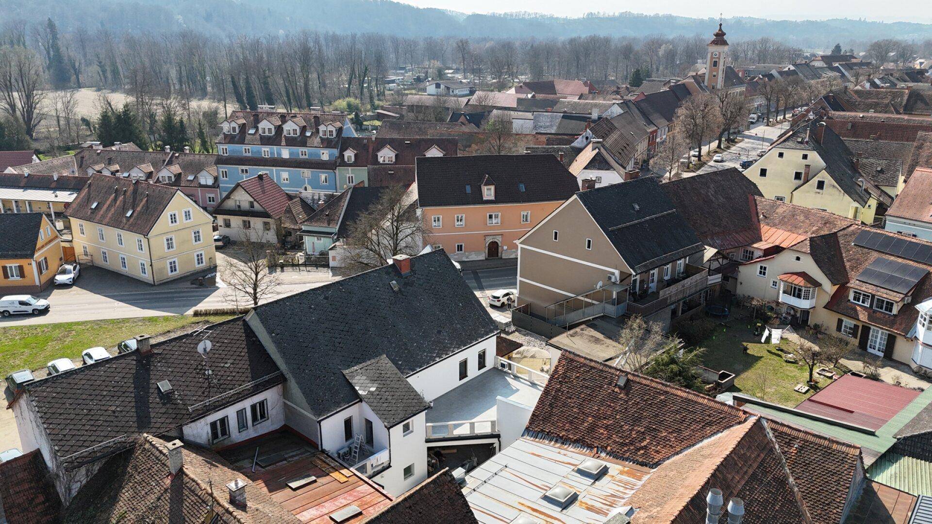Weitläufige Luftaufnahme einer ländlichen Stadt mit vielen Dächern und einem Kirchturm.
