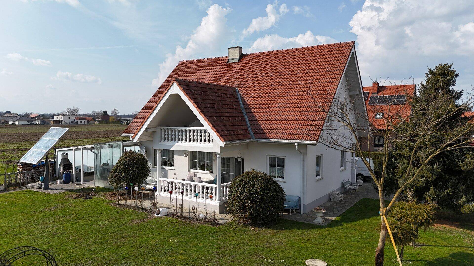 Freistehendes Einfamilienhaus mit Garten, Terrasse und Solaranlage auf dem Dach.