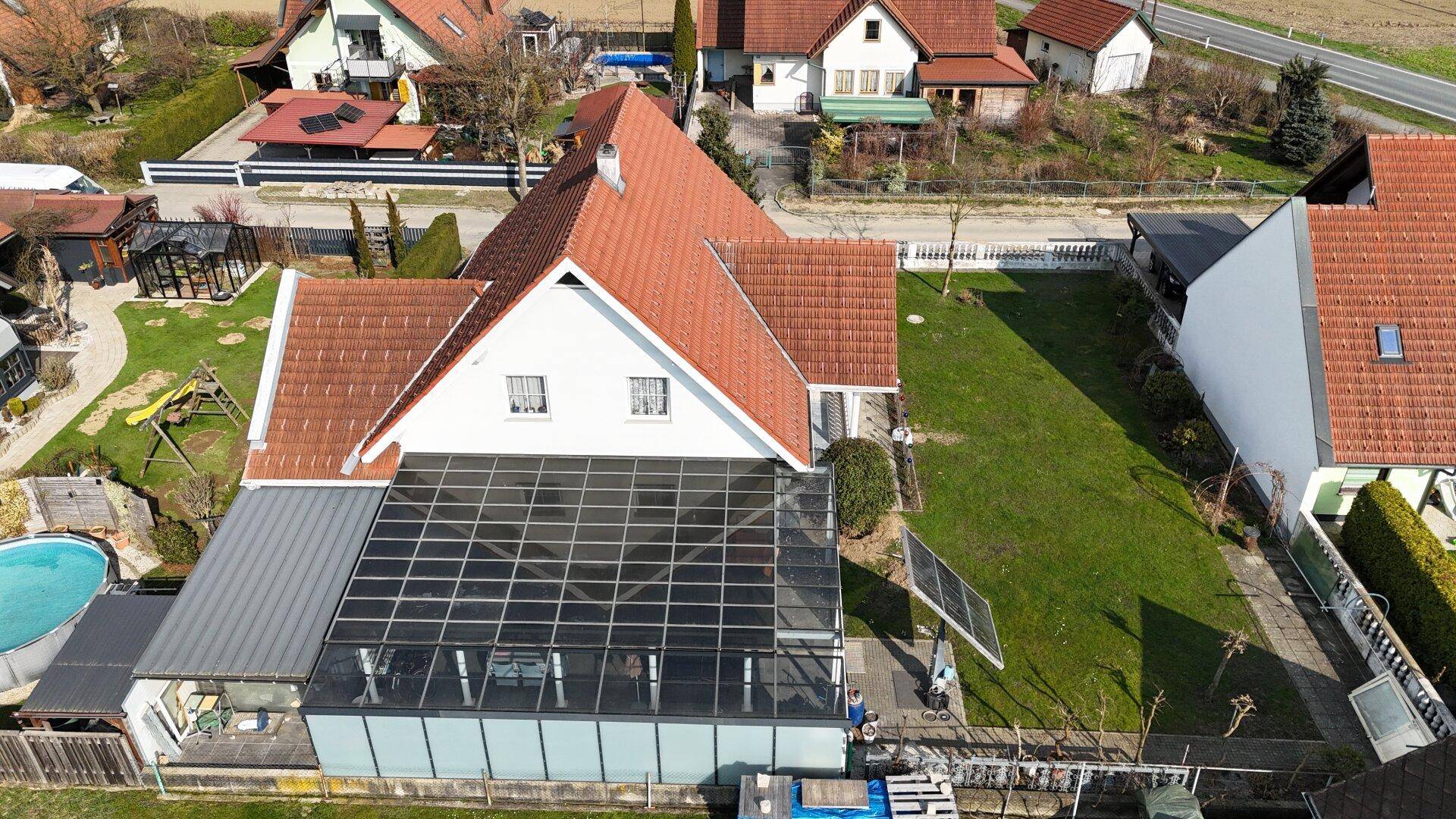 Vogelperspektive des Hauses mit Wintergarten, Pool und Solaranlage auf dem Dach.