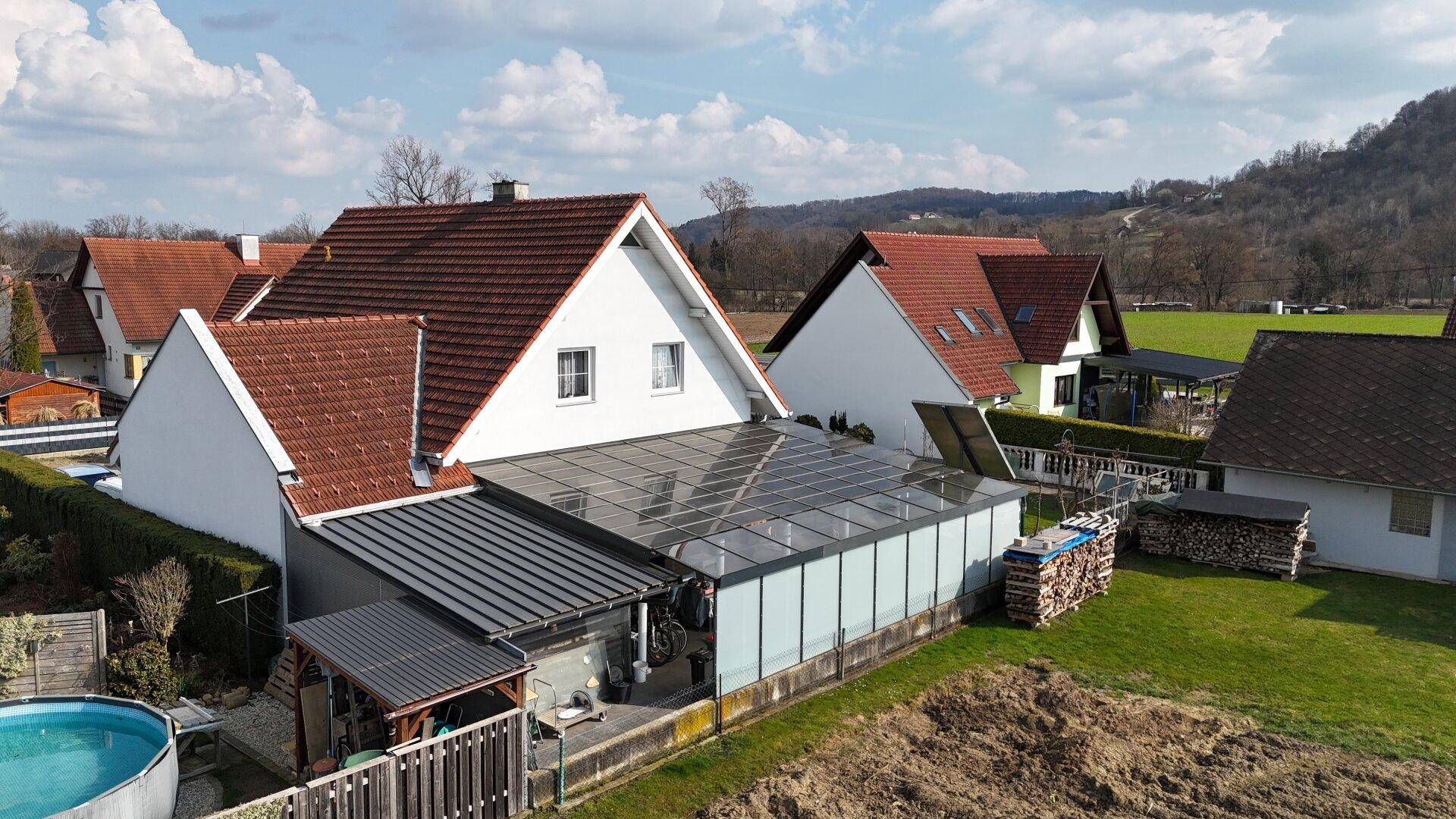 Luftaufnahme des Hauses mit Wintergarten, Pool und ländlicher Umgebung.
