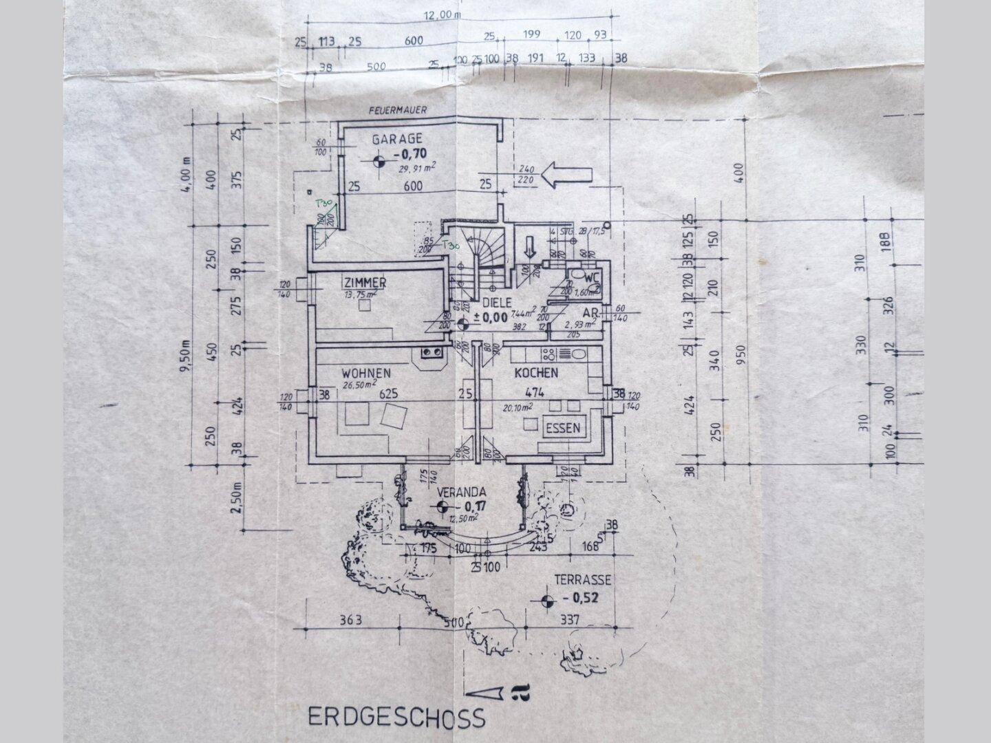 Grundriss des Erdgeschosses mit Wohnzimmer, Küche, Essbereich, Veranda, Terrasse und Garage.