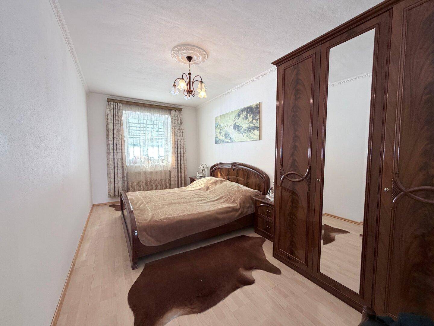 Schlafzimmer mit Parkettboden, großem Spiegelschrank und Doppelbett.