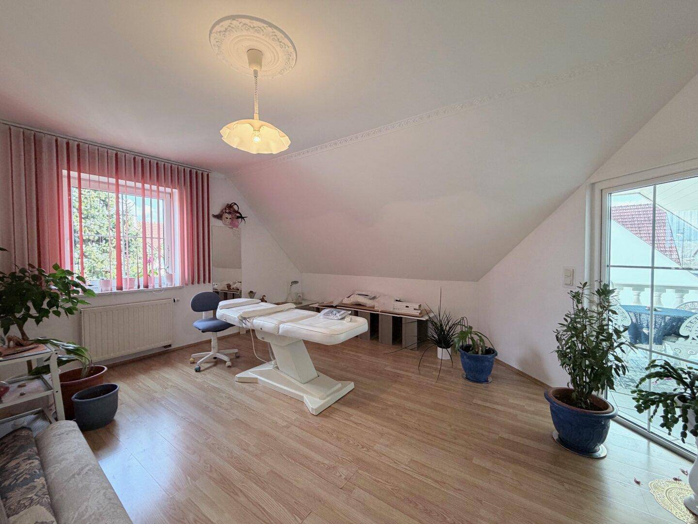 Vielseitig nutzbarer Raum im Dachgeschoss mit Parkettboden und großem Fenster.