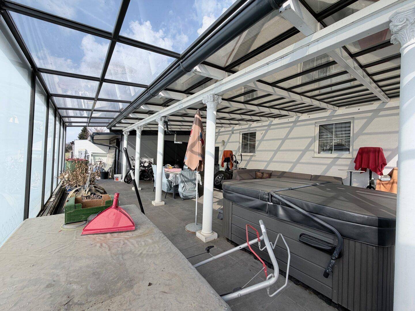 Überdachte Terrasse mit Whirlpool und Glasdach, ideal für Entspannung im Freien.