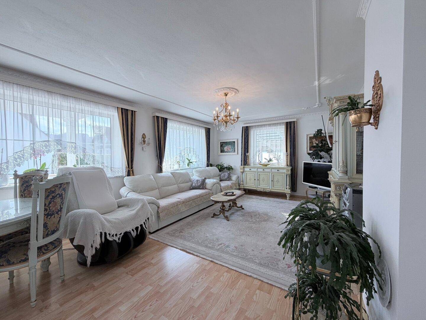 Helles Wohnzimmer mit Parkettboden, Stuckdecke und klassischer, eleganter Einrichtung.