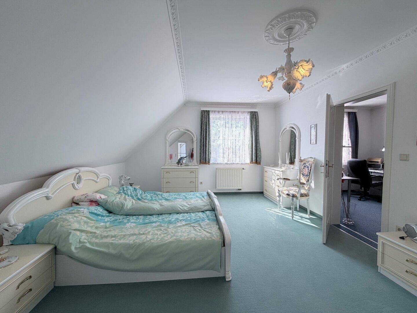 Schlafzimmer im Dachgeschoss mit Teppichboden, Schminktisch und Dachschräge.