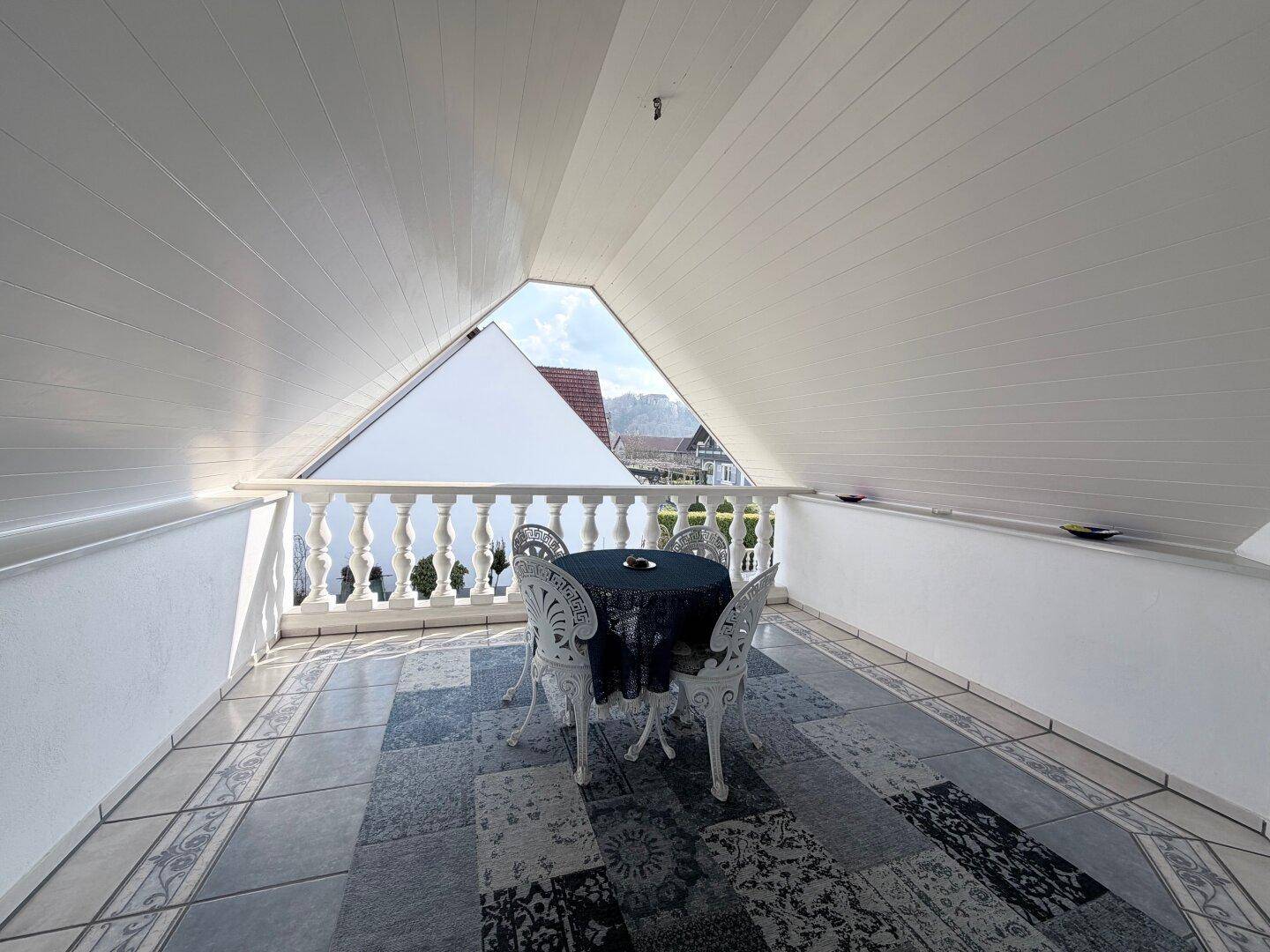 Überdachter Balkon im Dachgeschoss mit Balustrade und Blick auf die Nachbarschaft.