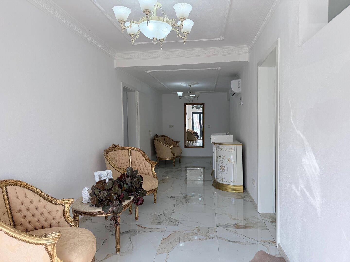 Geräumiger Flur mit Marmorboden, klassischen Möbeln und Stuckverzierungen an der Decke.