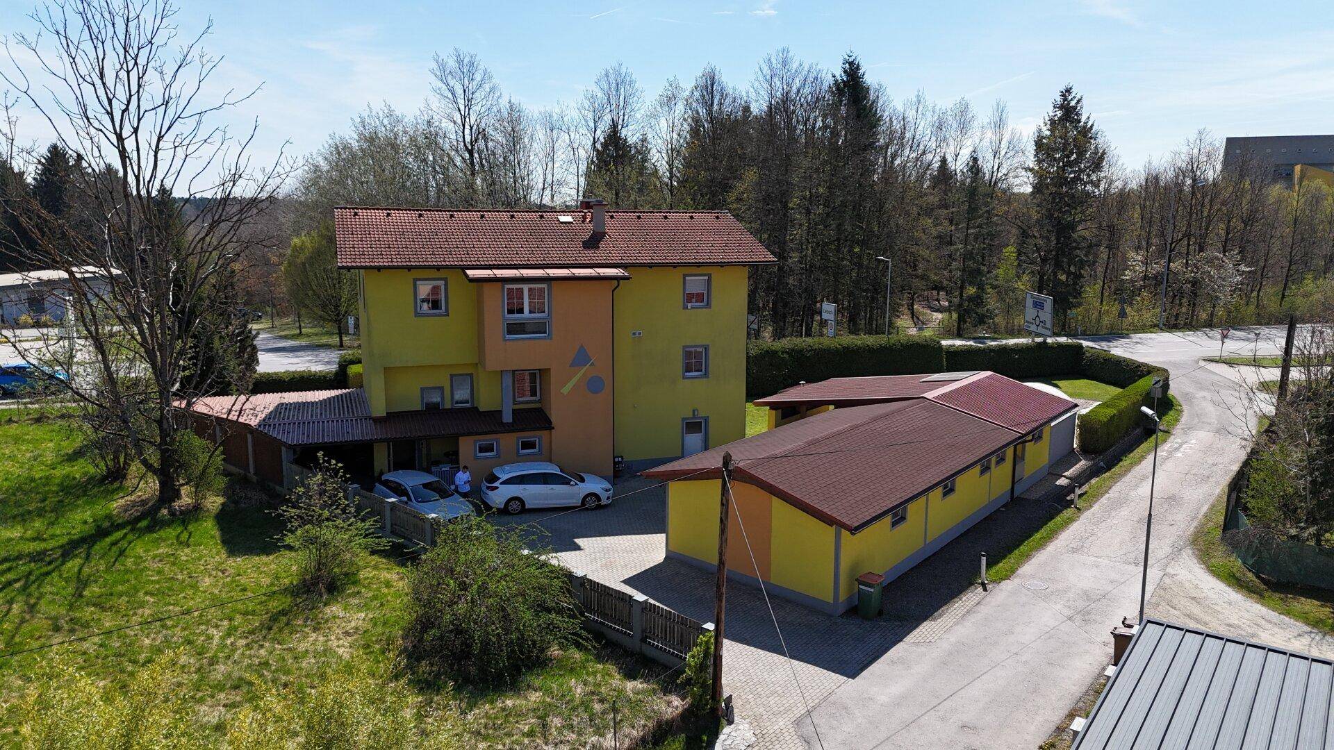 Vogelperspektive des Wohnhauses mit mehreren Stellplätzen und angrenzendem Nebengebäude.