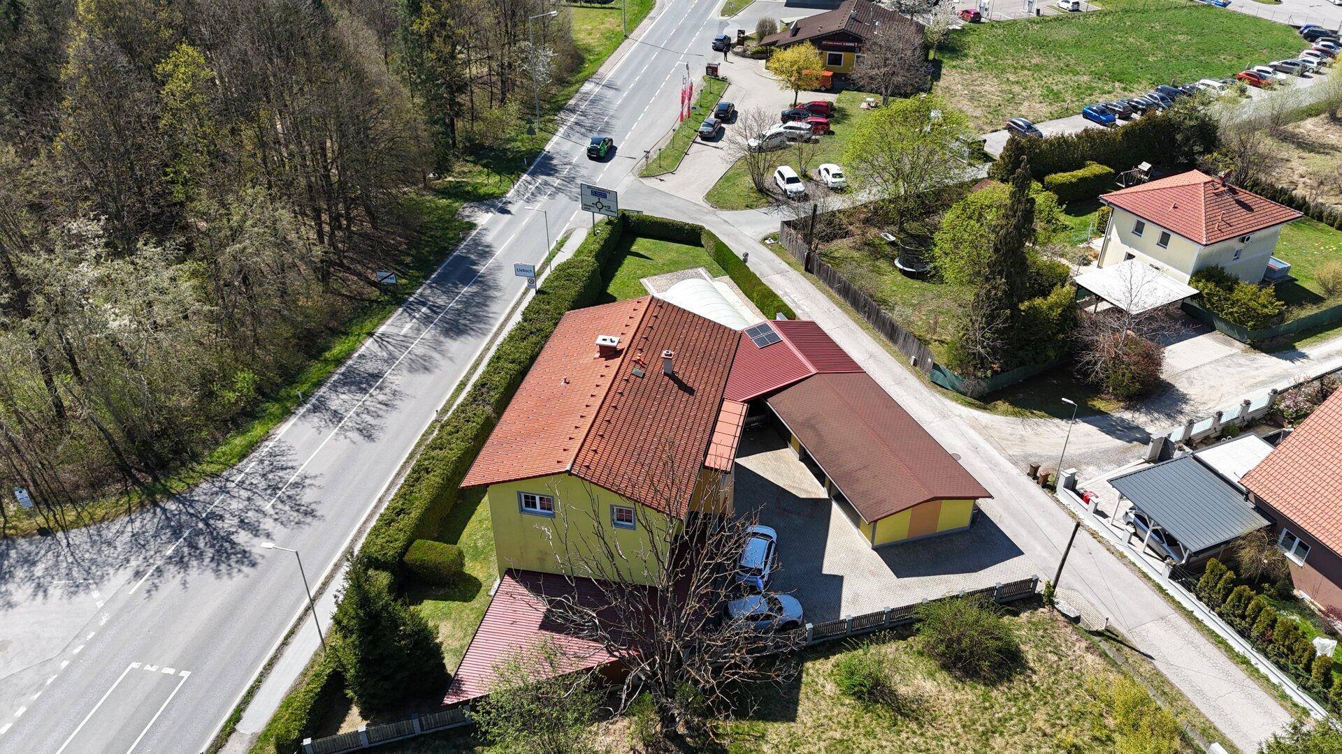 Weitläufige Luftaufnahme des Anwesens mit Hauptgebäude, Nebengebäuden und Zufahrtsstraßen.