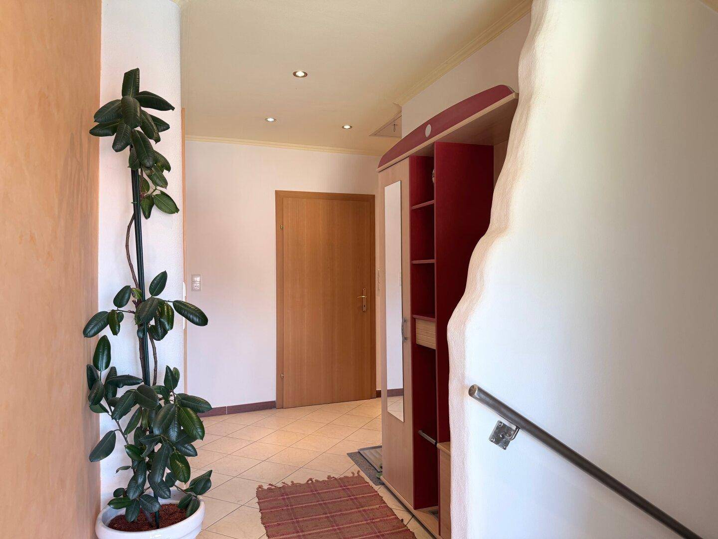 Heller Eingangsbereich mit Fliesenboden, Garderobe und Zugang zu weiteren Räumen.