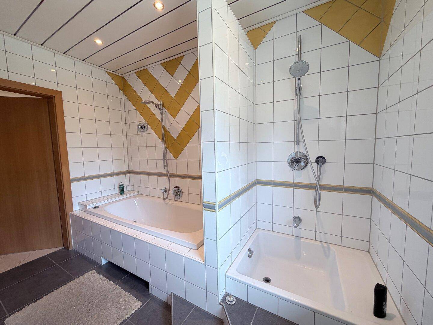 Geräumiges Badezimmer mit zwei Badewannen und gelb-weißen Wandfliesen.