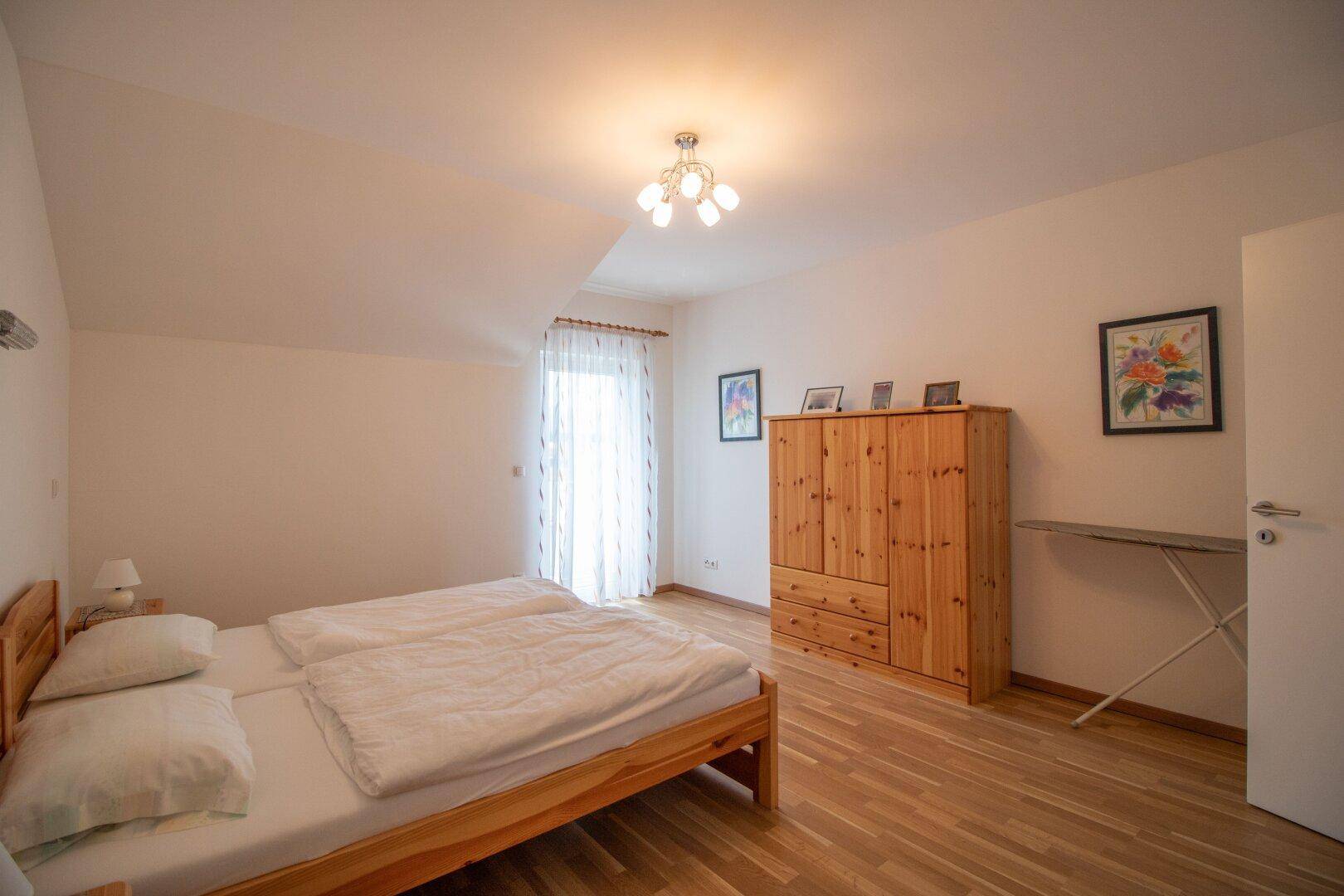 Gemütliches Schlafzimmer mit Holzbett, Kleiderschrank und hellem Holzfußboden.