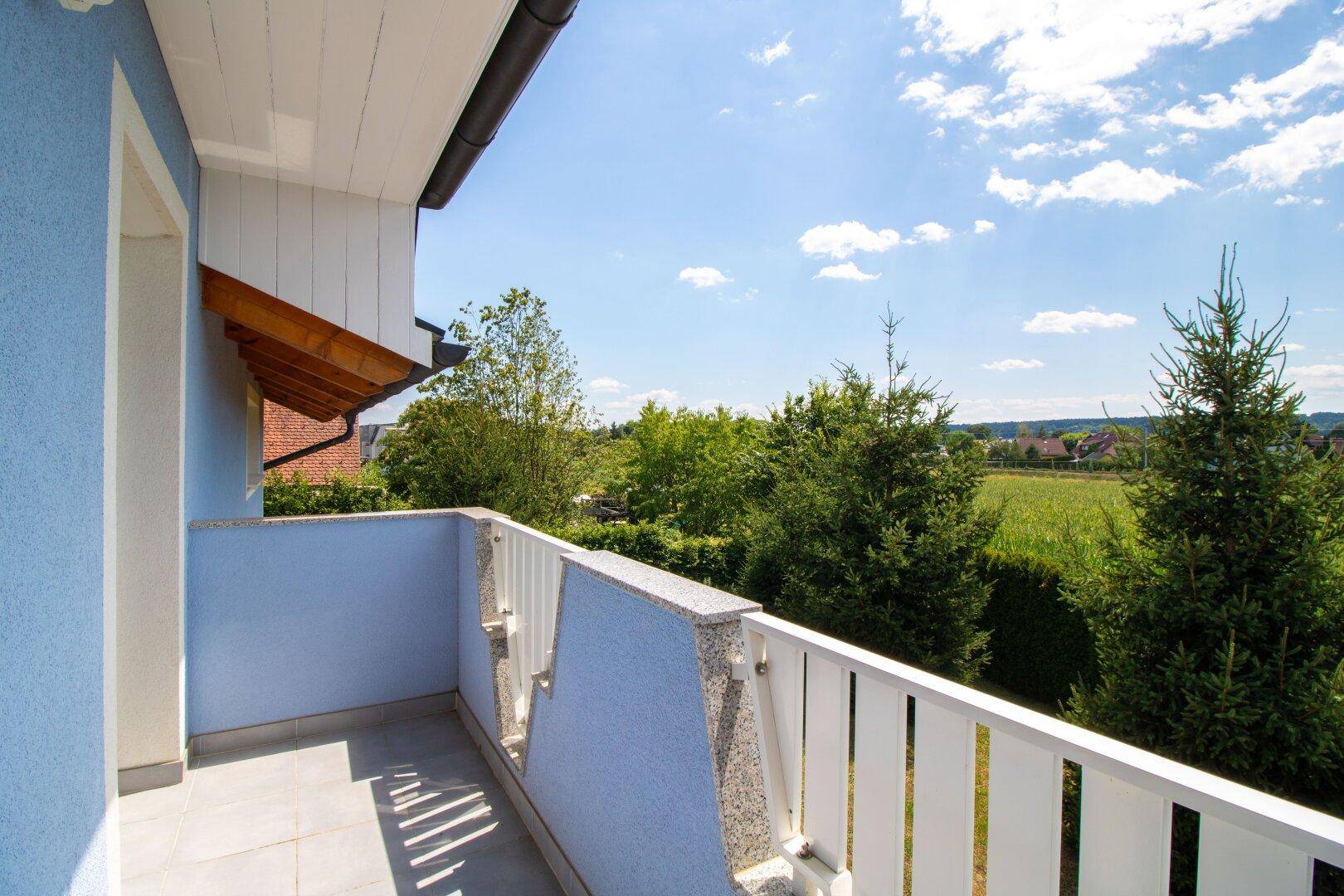 Heller Balkon mit Fliesenboden und schöner Aussicht auf die Natur.