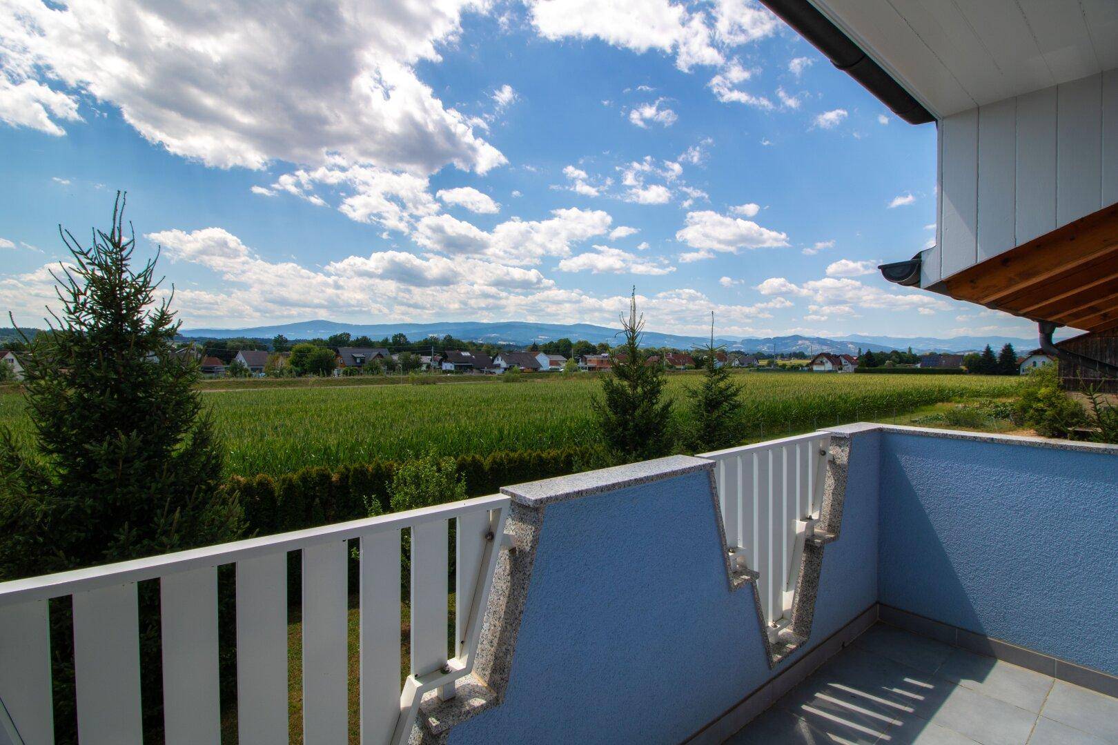Balkon mit weitem Blick über grüne Felder und die umliegende Landschaft.
