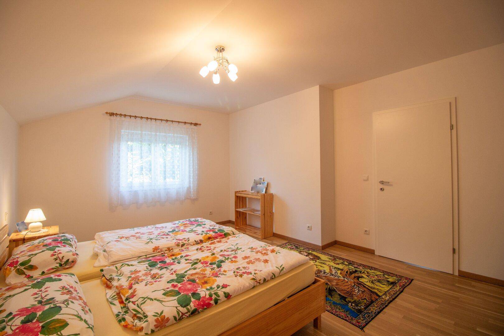 Schlafzimmer mit Holzbett, Nachttischen und Fenster mit Blick ins Grüne.