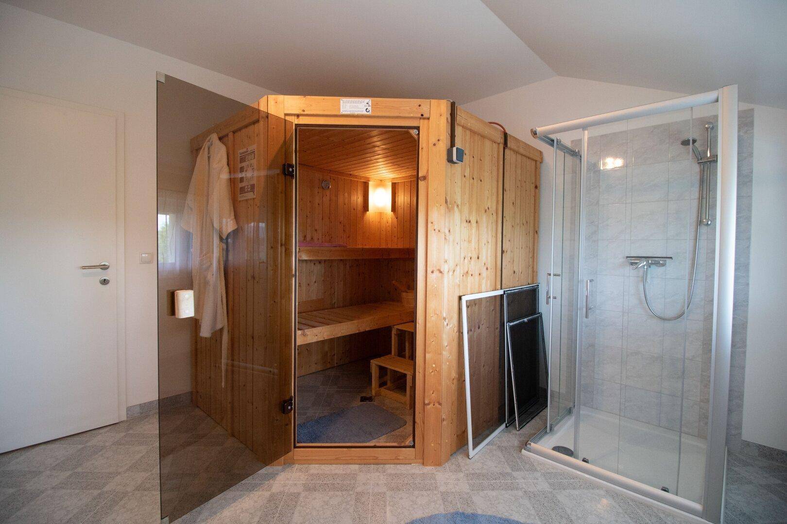 Wellnessbereich mit holzvertäfelter Sauna und separater Duschkabine.