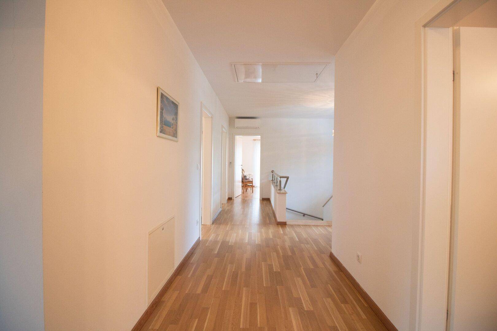 Langer, heller Flur mit Holzparkettboden und Zugang zu mehreren Räumen.