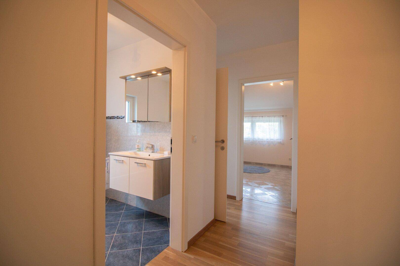 Flur mit Holzfußboden, der zu einem Badezimmer und einem weiteren Zimmer führt.