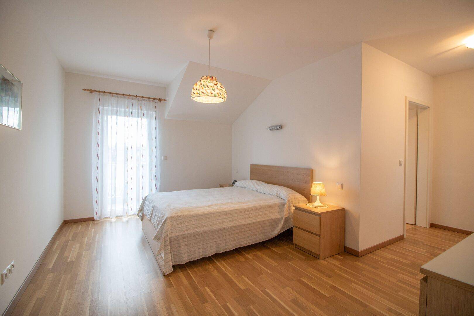 Schlafzimmer mit Doppelbett, Nachttisch und hellem Holzfußboden.