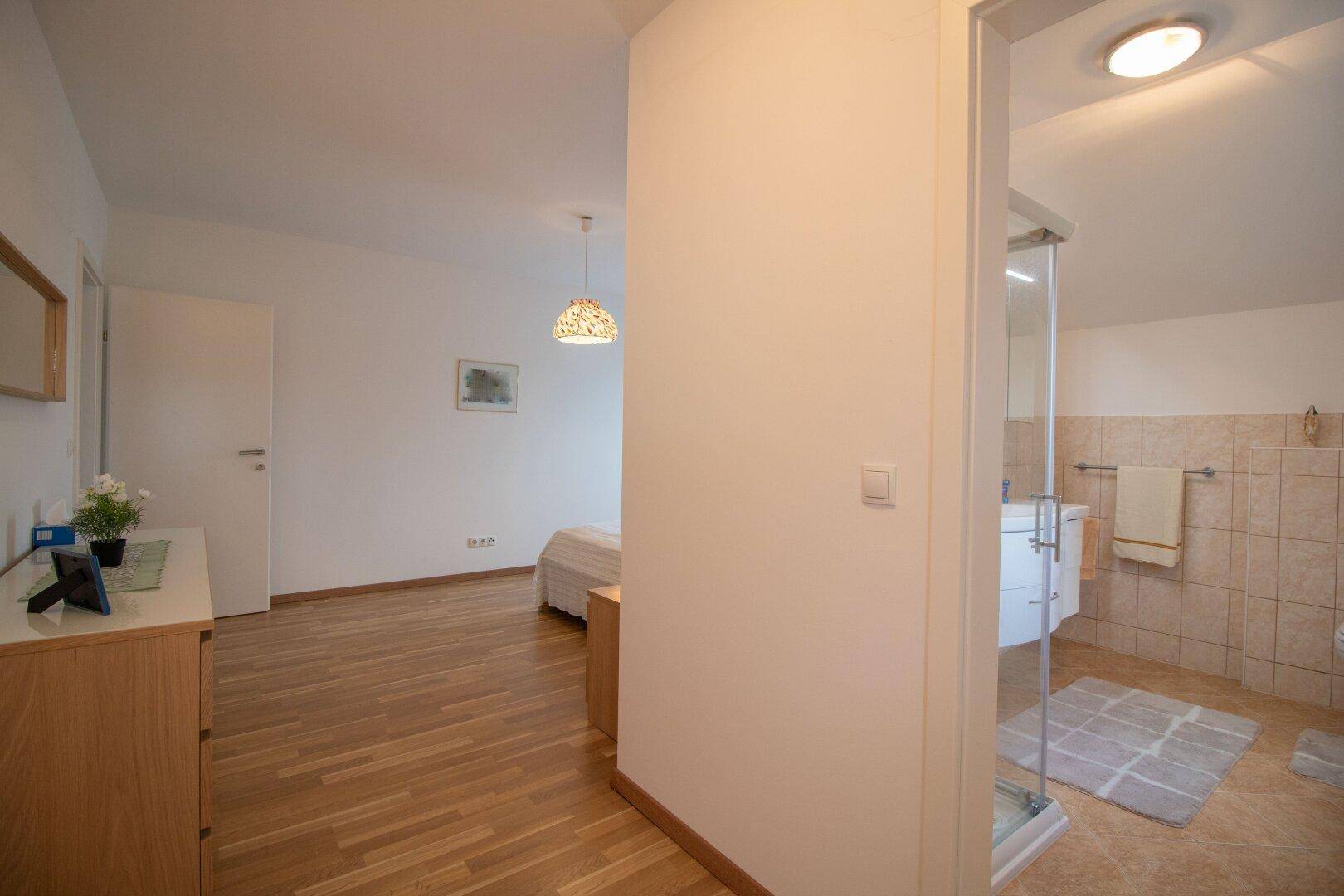 Flur mit Holzfußboden, der zu einem Schlafzimmer und einem Badezimmer führt.