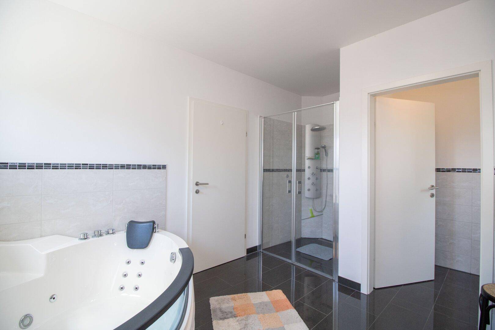 Geräumiges Badezimmer mit Whirlpool-Badewanne und separater Duschkabine.