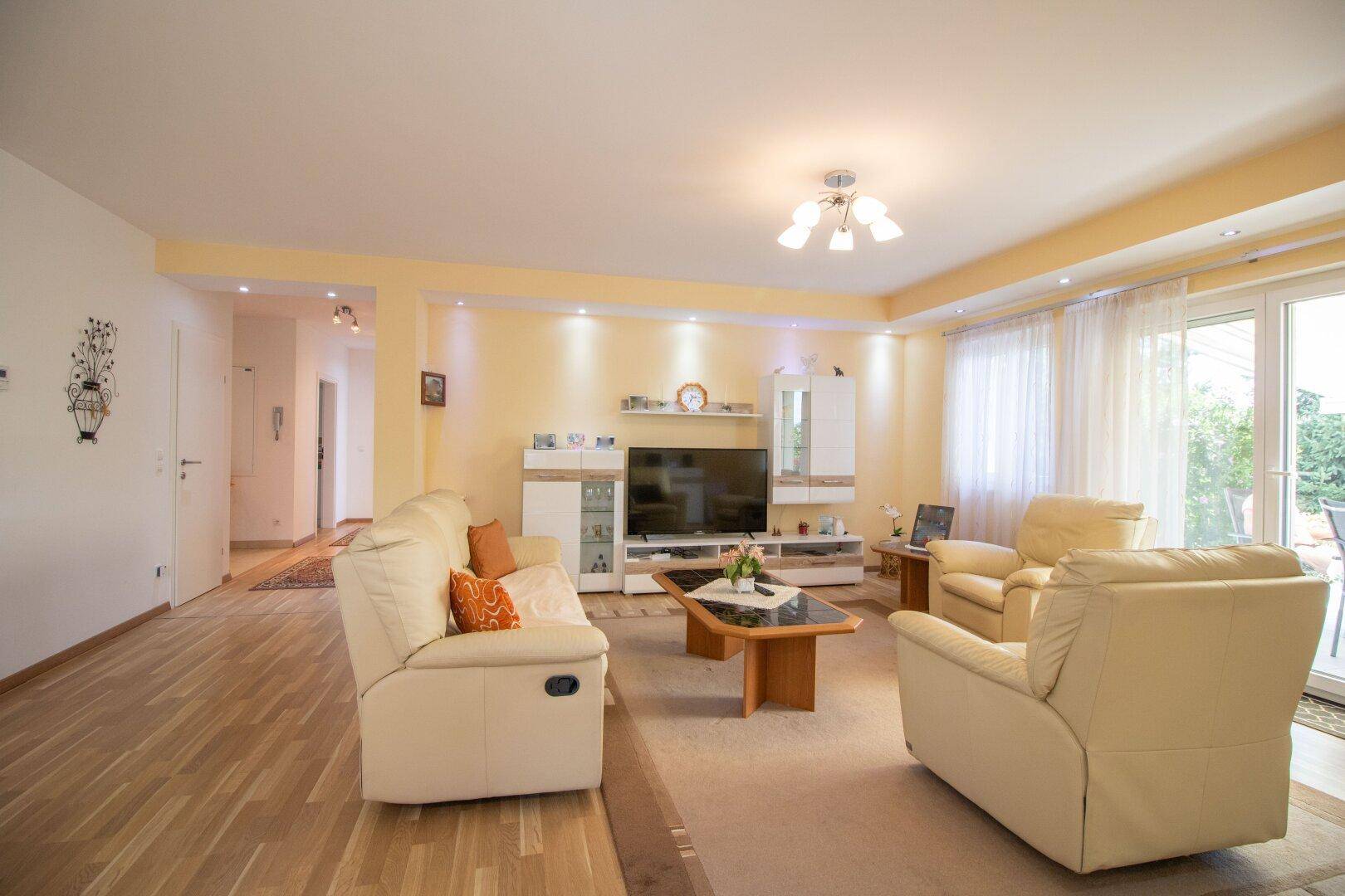 Gemütliches Wohnzimmer mit Parkettboden, TV-Möbeln und Zugang zur Terrasse.