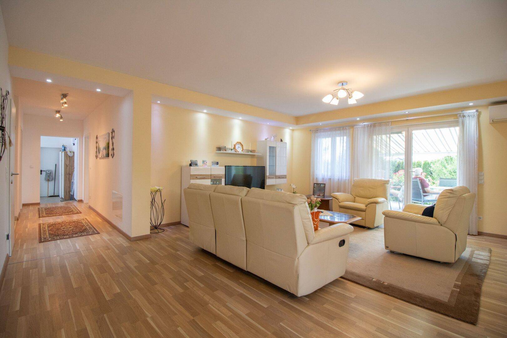 Helles Wohnzimmer mit bequemen Sofas, Parkettboden und Zugang zur Terrasse.