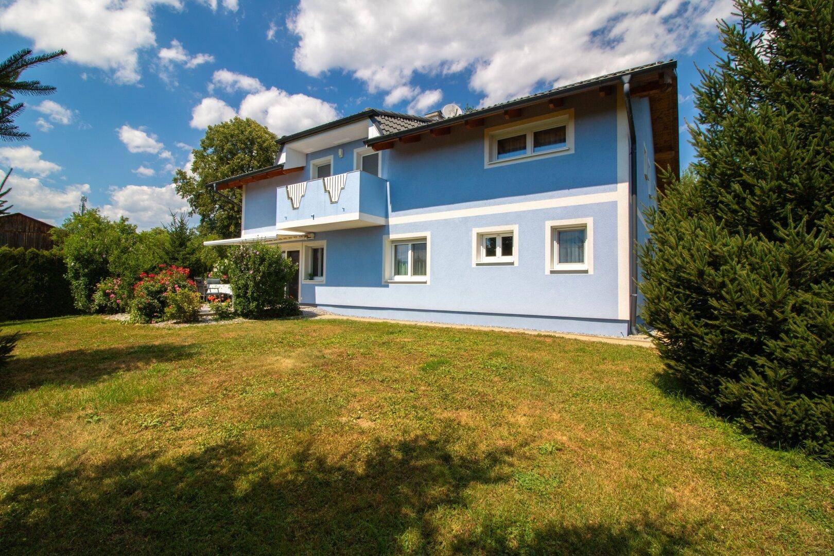 Ansicht des blauen Hauses mit Balkon und großem Gartenbereich.