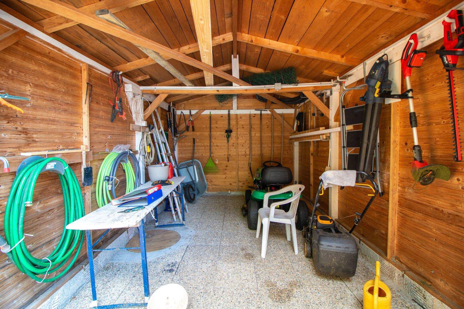 Gut ausgestattetes Gartenhaus mit vielen Geräten und Holzverkleidung.