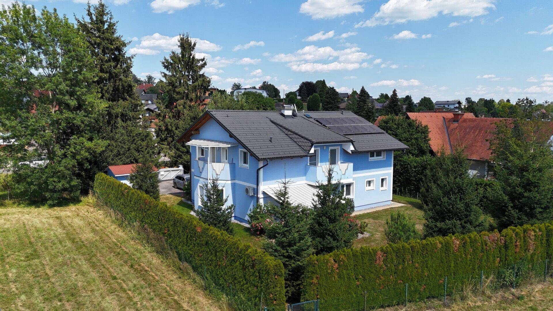 Luftaufnahme des Hauses mit Photovoltaikanlage auf dem Dach und umgebender Natur.