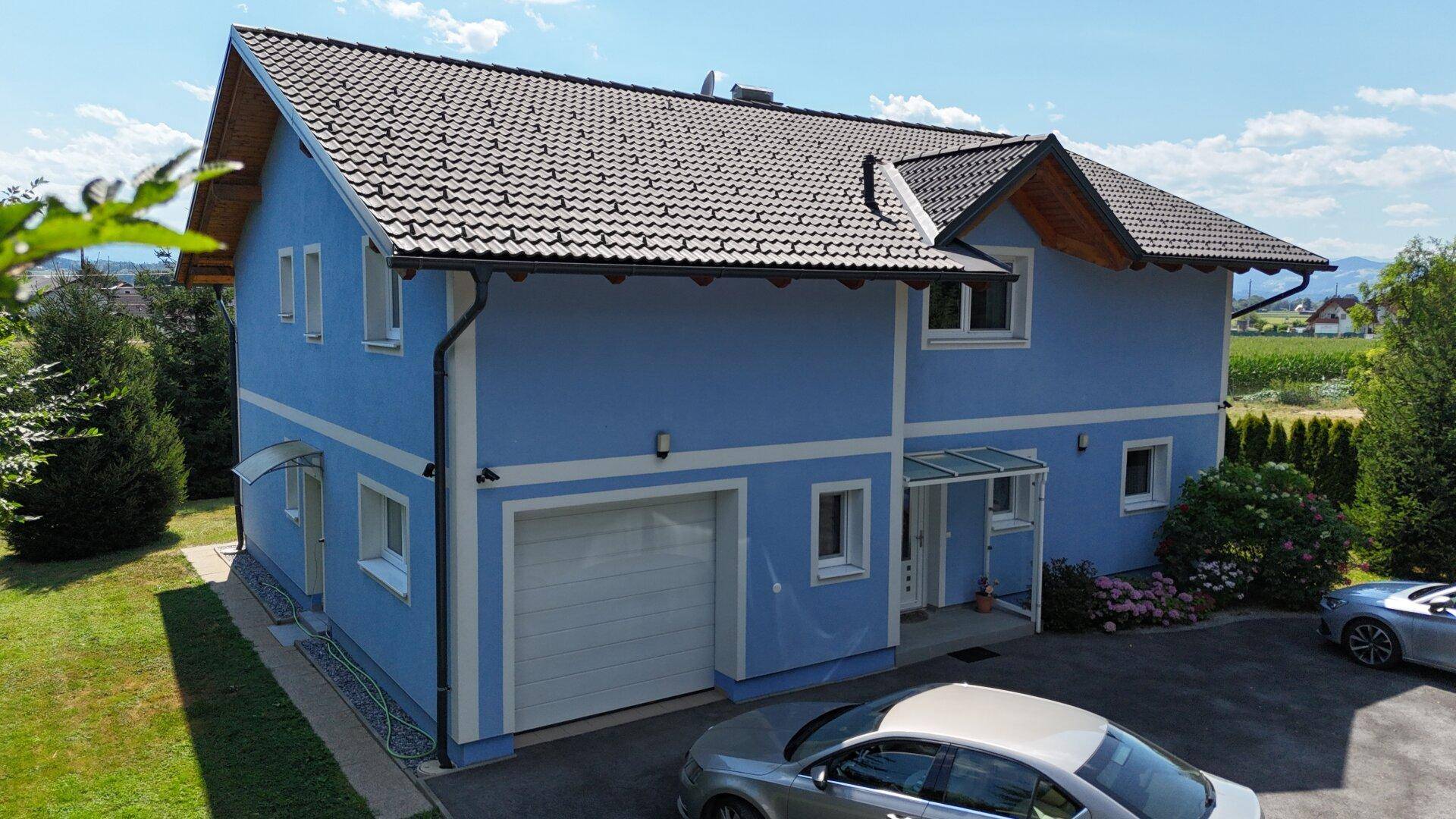 Ansicht des blauen Einfamilienhauses mit Garage und gepflegtem Vorgarten.