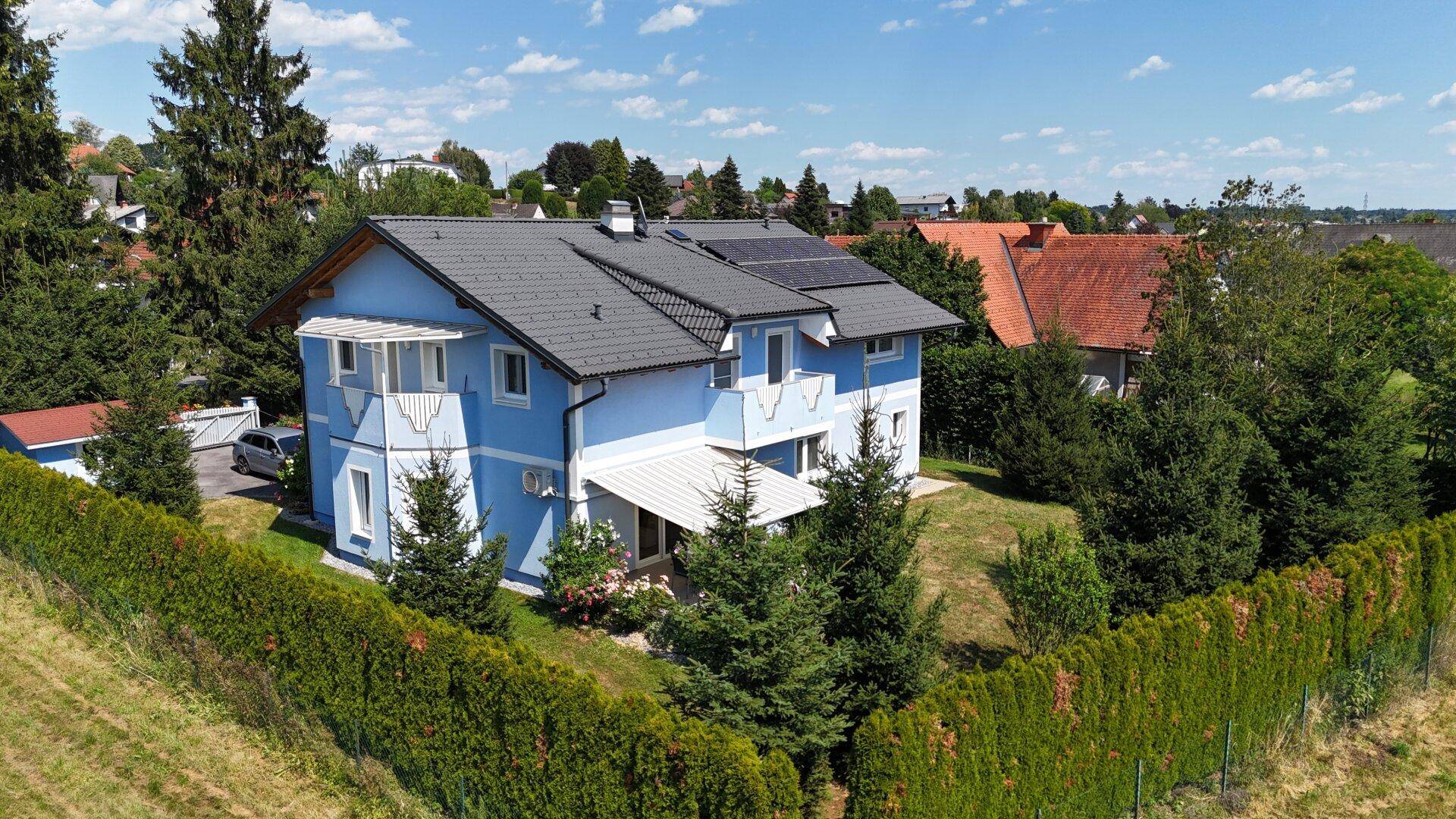 Wohnhaus mit Photovoltaik, Balkon und Garten in ländlicher Umgebung.