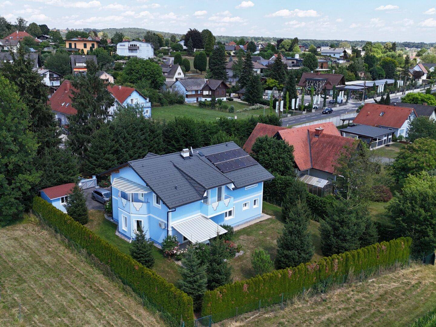 Weitläufige Ansicht des blauen Wohnhauses mit umliegender Natur und Nachbarschaft.