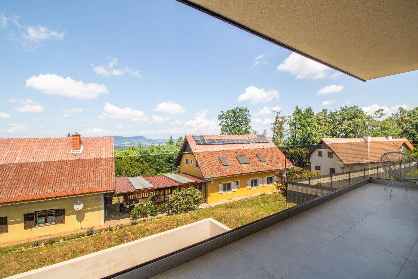Balkon mit Fliesenboden und Panoramablick auf die umliegende Wohngegend und Berge.